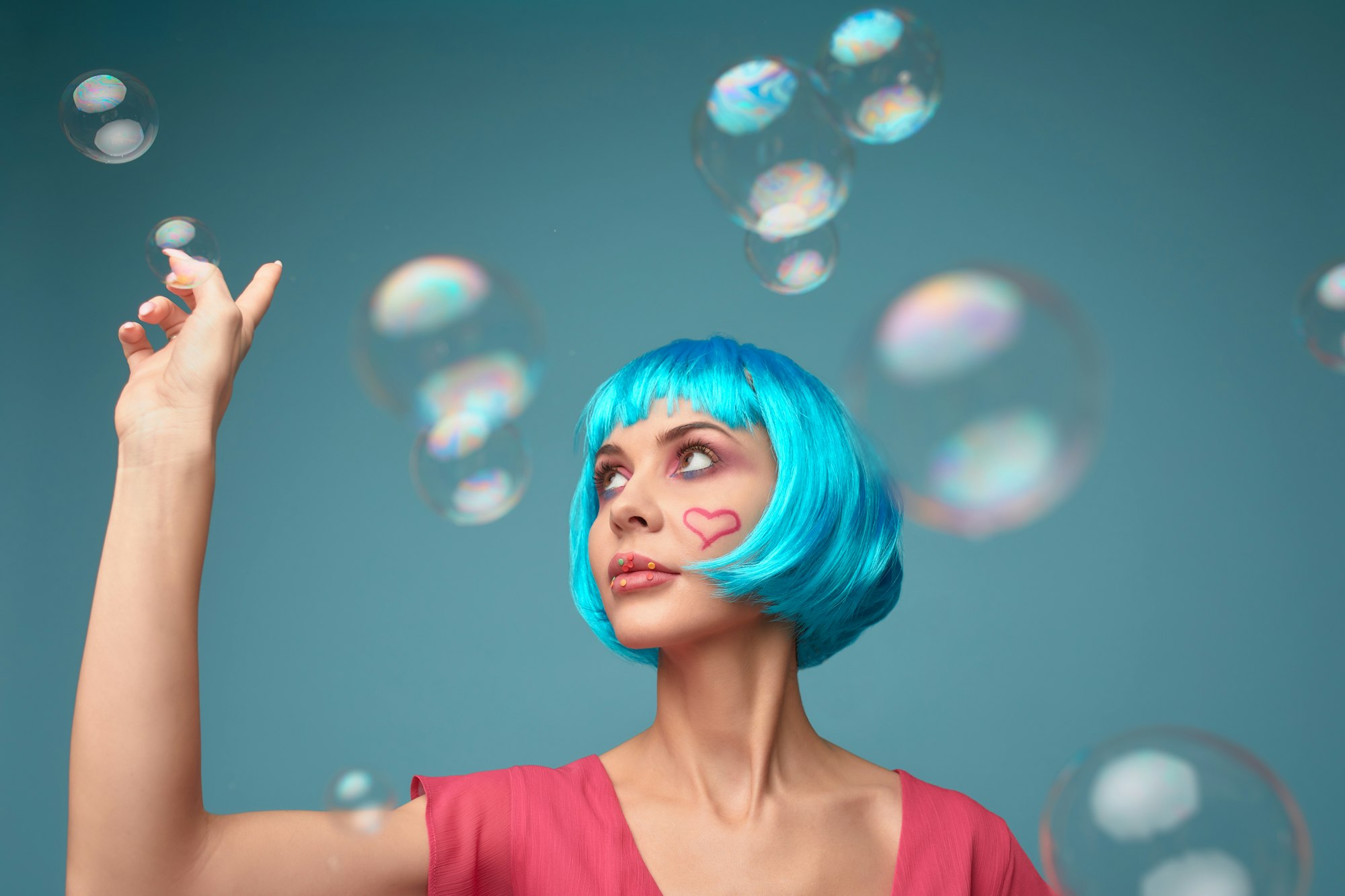 Beautiful young woman with blue wig and bright make-up in soap bubbles. Fashion model girl with