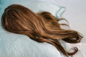 Closeup of a brunette wig with highlights on a silk pillow