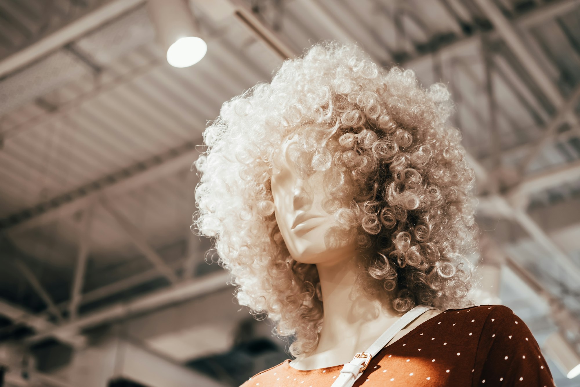 Mannequin in curly wigs stand in clothing store. Shopping, fashion and advertisement background